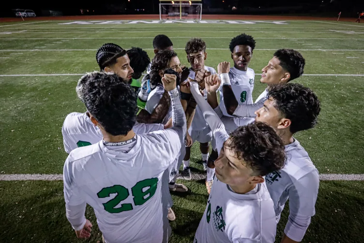 Football team in white kits gathering for a huddle